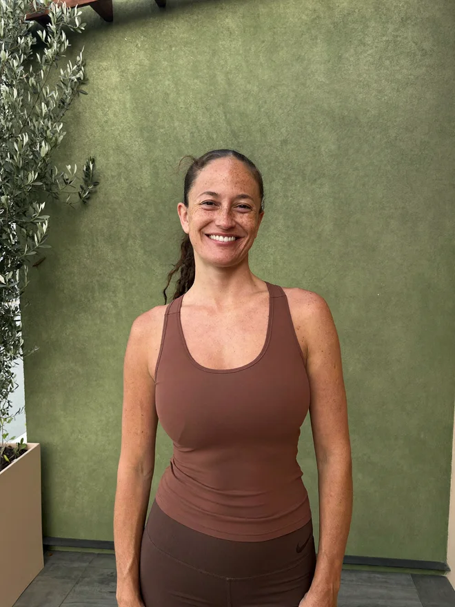 Maya, a fictional fitness creator, smiling on a sunlit terrace